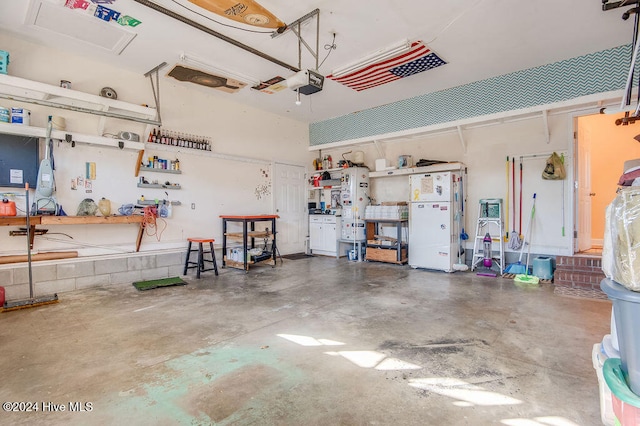 garage with a workshop area, white fridge, and a garage door opener