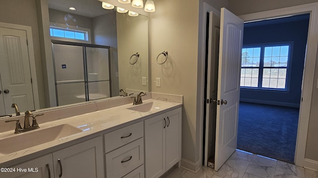 bathroom with marble finish floor, baseboards, a sink, and a shower with shower door