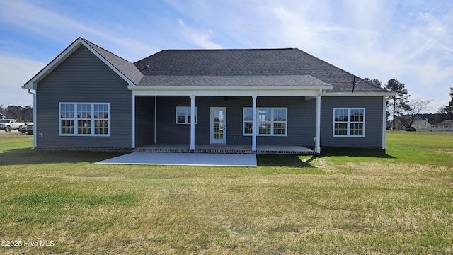 back of property featuring a ceiling fan, a lawn, a shingled roof, and a patio