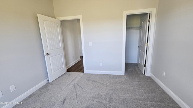 unfurnished bedroom featuring a spacious closet, baseboards, and carpet flooring