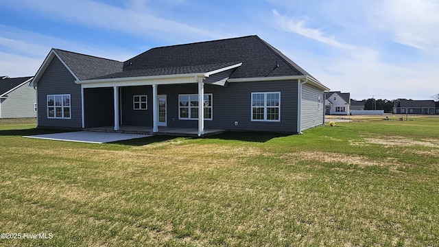 back of property with a patio area, a lawn, and roof with shingles