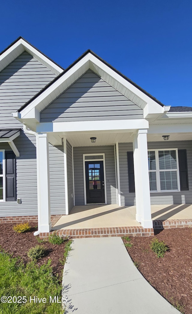 view of exterior entry featuring covered porch