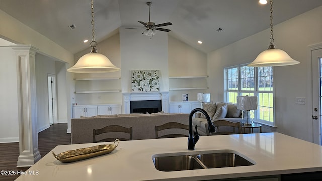 kitchen with dark wood-style floors, a fireplace, decorative columns, visible vents, and a sink