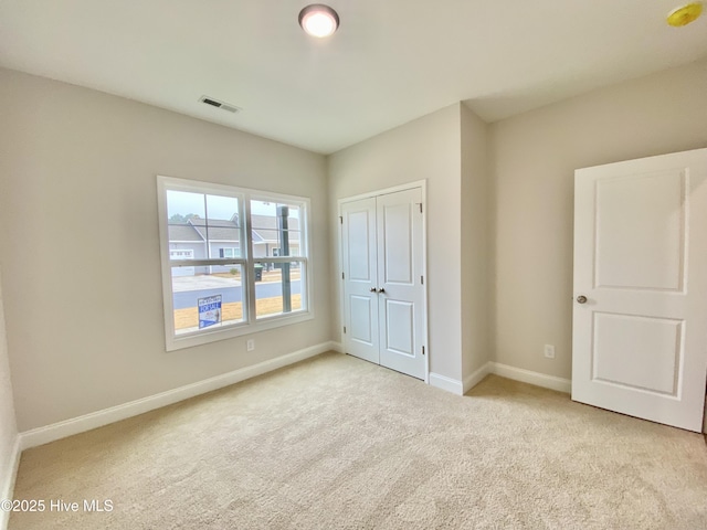 unfurnished bedroom with light colored carpet and a closet