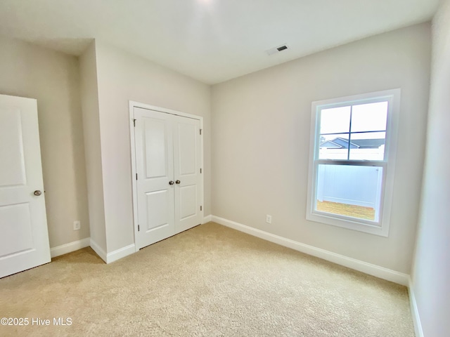 unfurnished bedroom featuring light colored carpet and a closet