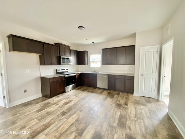 kitchen featuring stainless steel appliances, decorative light fixtures, light hardwood / wood-style floors, and decorative backsplash