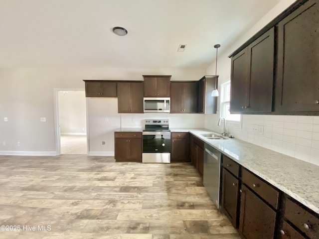 kitchen with appliances with stainless steel finishes, sink, decorative backsplash, hanging light fixtures, and dark brown cabinets