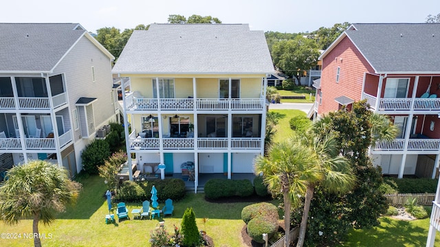 back of house with a balcony, a lawn, and a patio