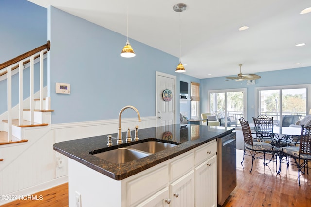 kitchen featuring light hardwood / wood-style floors, white cabinetry, sink, pendant lighting, and a kitchen island with sink