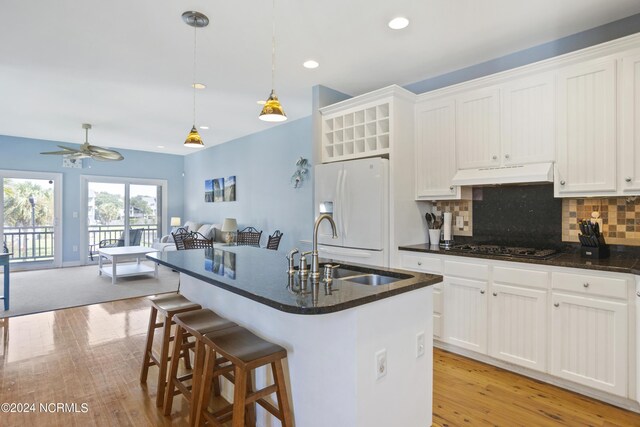 kitchen with wood finished floors, a sink, open floor plan, hanging light fixtures, and dishwasher