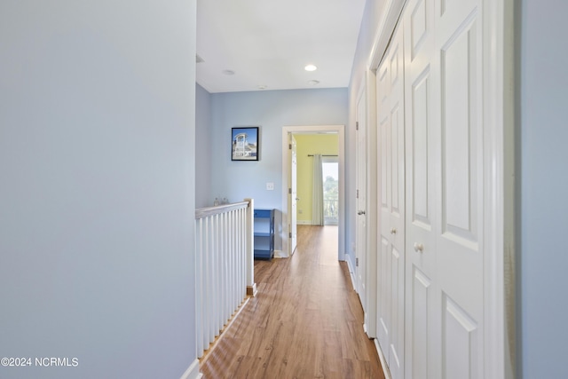 corridor featuring light wood-style flooring, baseboards, and recessed lighting