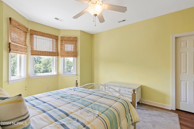 bedroom featuring ceiling fan, hardwood / wood-style floors, and multiple windows