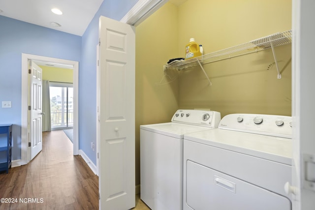 clothes washing area featuring laundry area, baseboards, wood finished floors, washing machine and clothes dryer, and recessed lighting