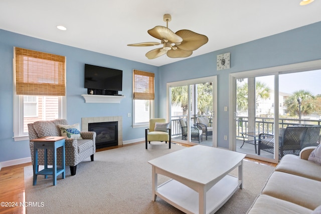 living room with ceiling fan, hardwood / wood-style flooring, and a tiled fireplace