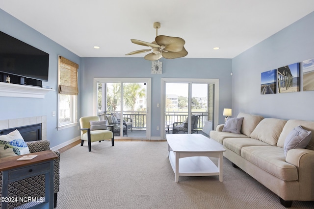 living area featuring baseboards, recessed lighting, a tiled fireplace, and a healthy amount of sunlight