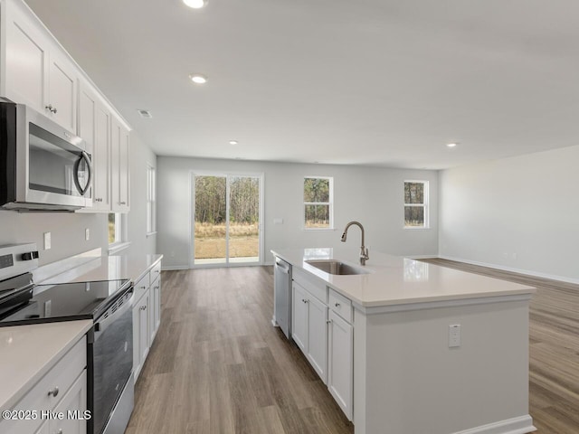 kitchen featuring an island with sink, appliances with stainless steel finishes, sink, and white cabinetry