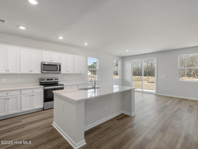 kitchen featuring white cabinetry, light hardwood / wood-style floors, an island with sink, stainless steel appliances, and sink