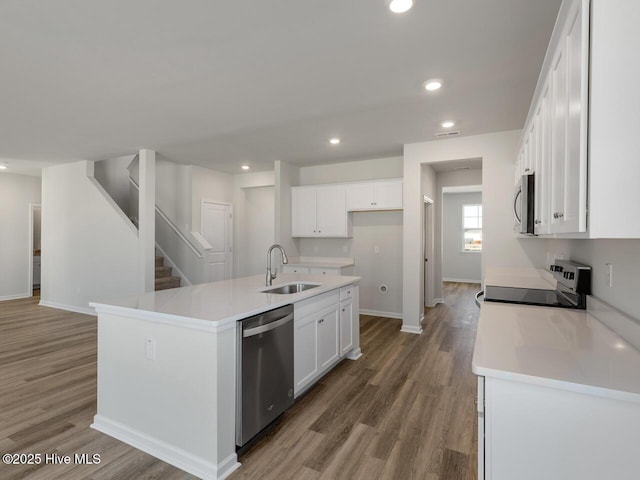 kitchen featuring an island with sink, appliances with stainless steel finishes, sink, and white cabinetry