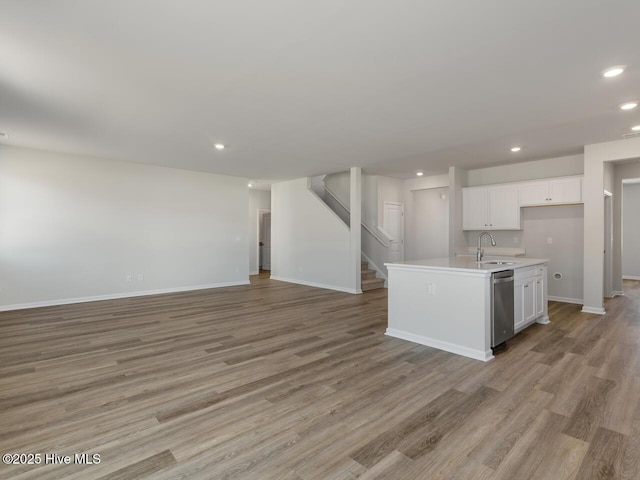 kitchen featuring white cabinets, dishwasher, an island with sink, sink, and light wood-type flooring