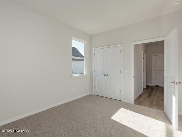 unfurnished bedroom with light colored carpet and a closet