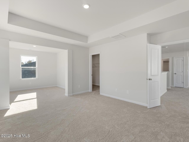 carpeted spare room featuring a tray ceiling