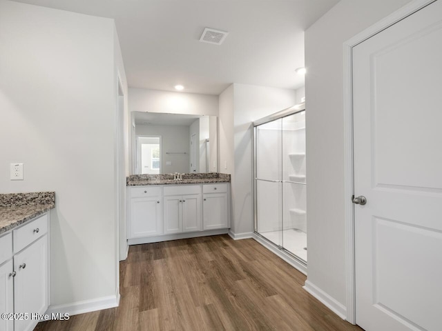 bathroom with wood-type flooring, walk in shower, and vanity