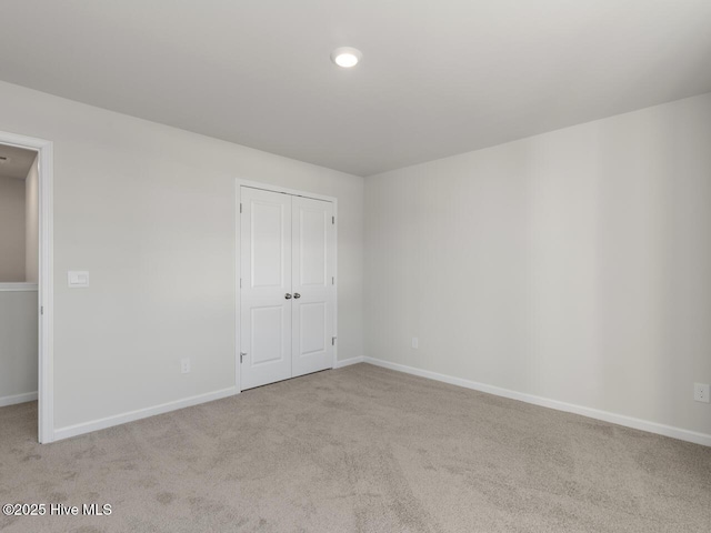 unfurnished bedroom featuring light colored carpet and a closet