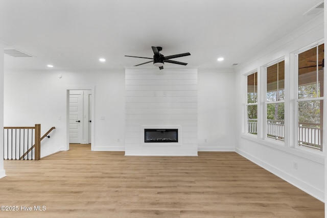 unfurnished living room with a fireplace, ornamental molding, ceiling fan, and light wood-type flooring