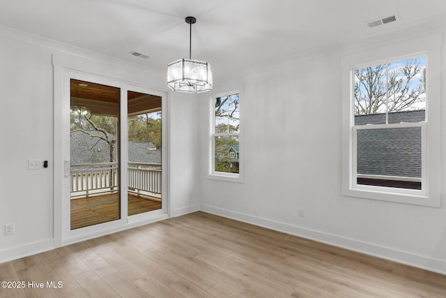 unfurnished dining area with crown molding, a notable chandelier, and light hardwood / wood-style floors