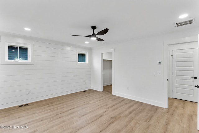 spare room featuring ceiling fan, wooden walls, and light hardwood / wood-style flooring