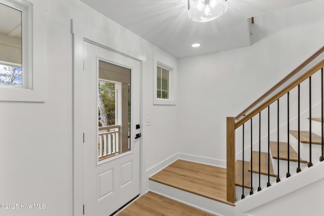 entrance foyer featuring a wealth of natural light, an inviting chandelier, and light hardwood / wood-style flooring