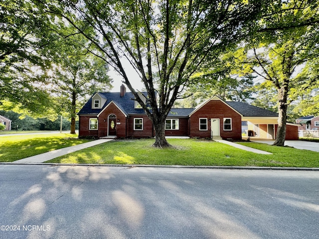 view of front of home featuring brick siding, a front lawn, and a chimney