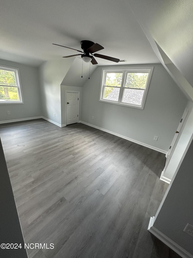 additional living space with dark wood-style flooring, vaulted ceiling, baseboards, and ceiling fan