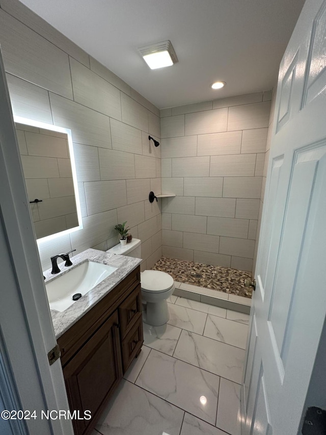 full bath with toilet, vanity, tile walls, marble finish floor, and a stall shower