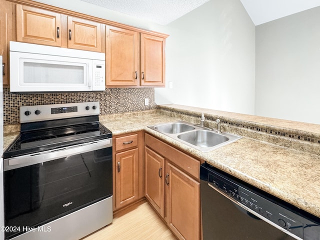 kitchen with backsplash, sink, light hardwood / wood-style flooring, a textured ceiling, and appliances with stainless steel finishes