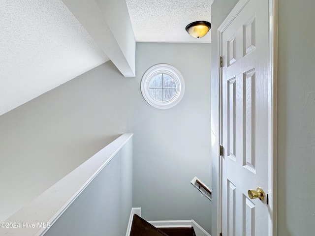 stairway featuring a textured ceiling