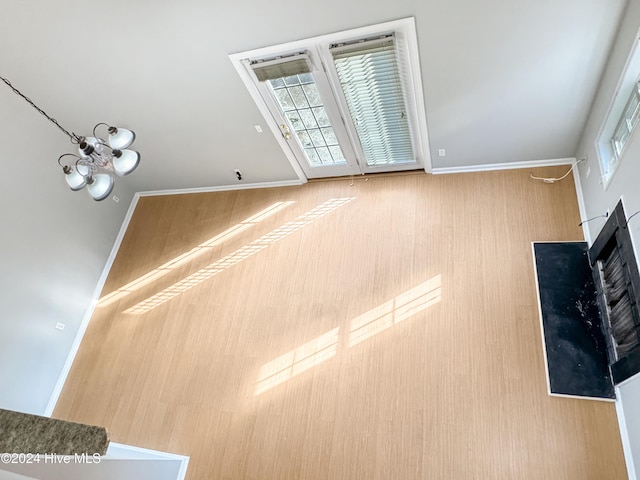 unfurnished living room with a chandelier, hardwood / wood-style floors, and basketball hoop