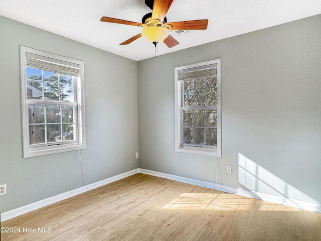 empty room featuring ceiling fan, plenty of natural light, a textured ceiling, and light hardwood / wood-style flooring