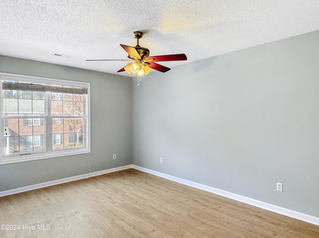 spare room with ceiling fan, light wood-type flooring, and a textured ceiling