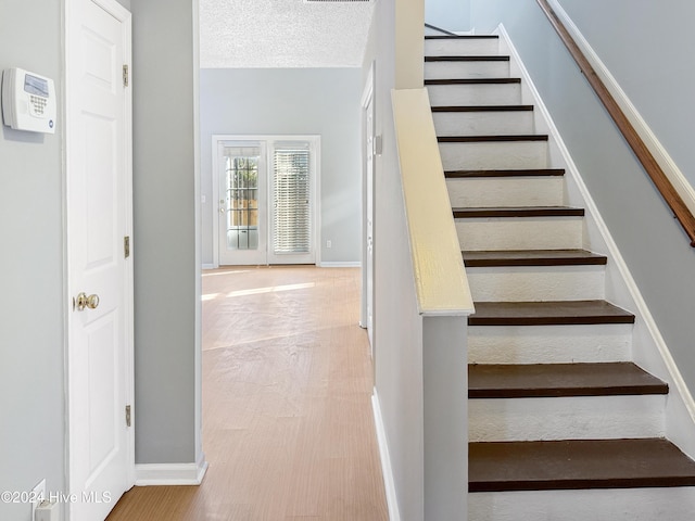 staircase with hardwood / wood-style floors and a textured ceiling