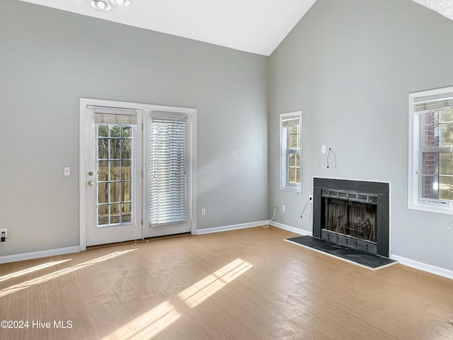 unfurnished living room with light wood-type flooring, high vaulted ceiling, and a wealth of natural light