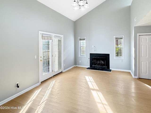 unfurnished living room with plenty of natural light, light hardwood / wood-style floors, and high vaulted ceiling