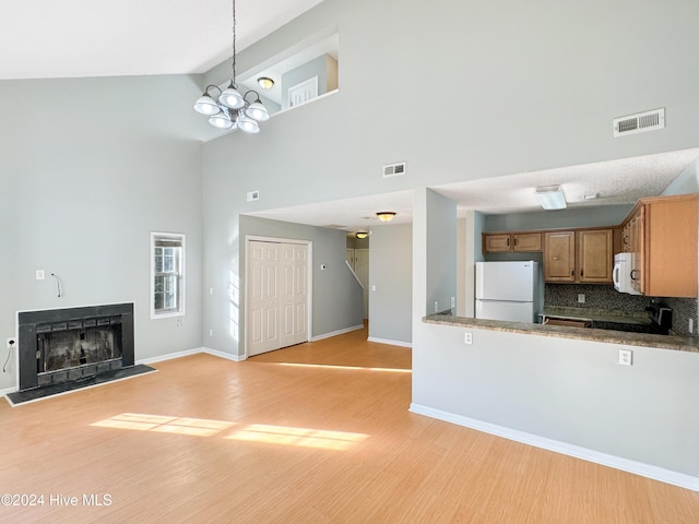 kitchen featuring backsplash, white appliances, beam ceiling, an inviting chandelier, and light hardwood / wood-style flooring