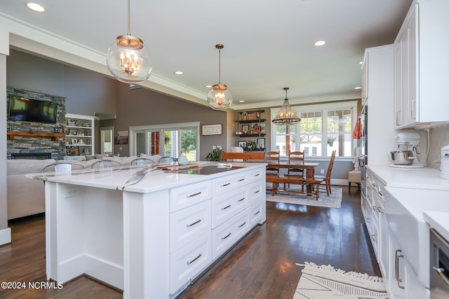 kitchen with pendant lighting, a kitchen island, light stone counters, and white cabinetry