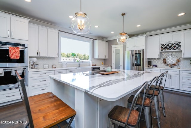 kitchen with white cabinetry, stainless steel appliances, and hanging light fixtures