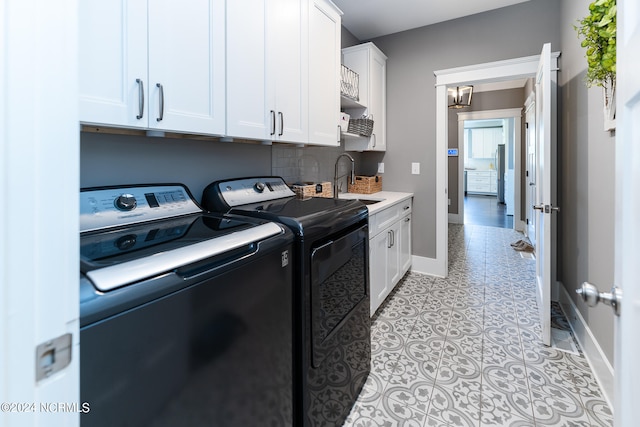 washroom with washing machine and clothes dryer, sink, cabinets, a notable chandelier, and light tile patterned floors