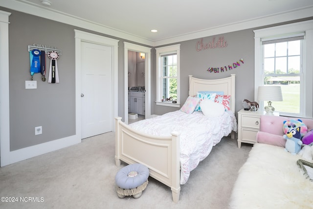 bedroom featuring ensuite bath, light carpet, and crown molding