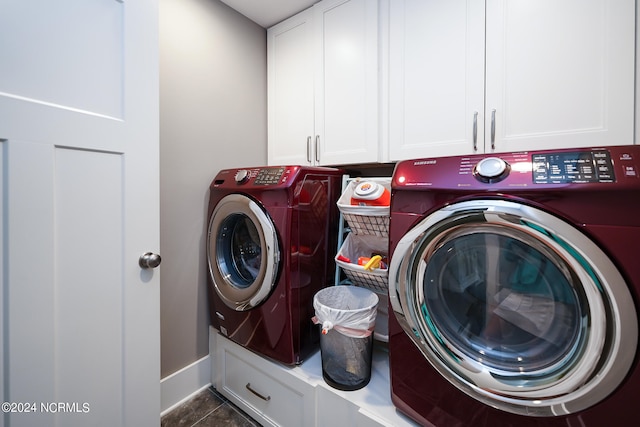 washroom featuring dark tile patterned flooring, cabinets, and washing machine and clothes dryer