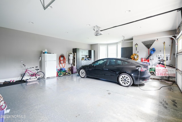 garage featuring white fridge and a garage door opener