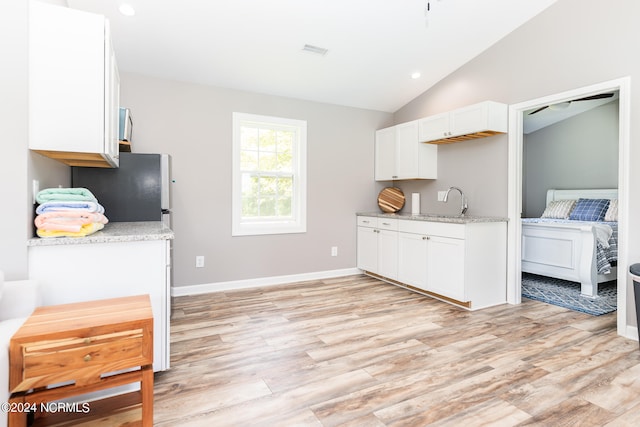 kitchen with white cabinetry, lofted ceiling, and light wood-type flooring